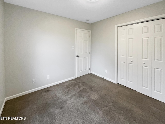 unfurnished bedroom featuring dark colored carpet and a closet