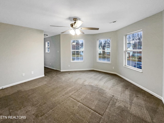 unfurnished room with dark colored carpet and ceiling fan