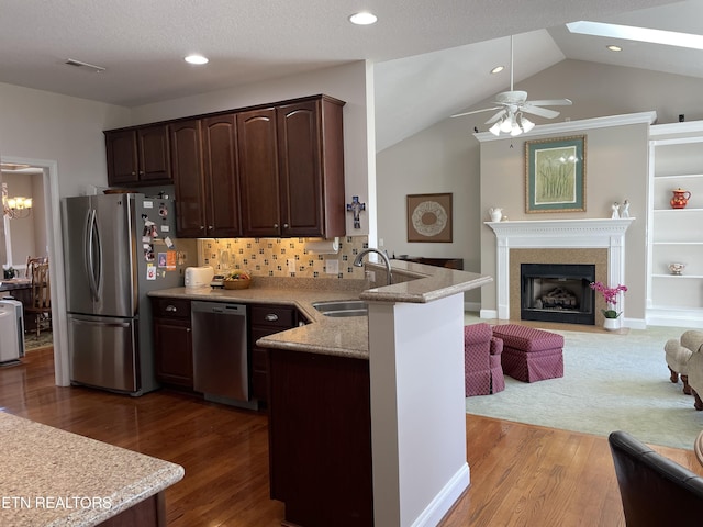 kitchen with sink, stainless steel appliances, dark brown cabinetry, wood-type flooring, and kitchen peninsula