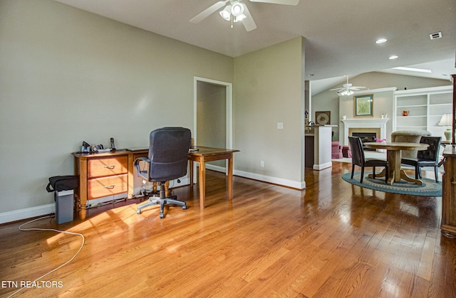home office with ceiling fan, wood-type flooring, and vaulted ceiling