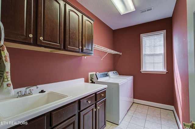laundry room with sink, cabinets, a textured ceiling, light tile patterned floors, and independent washer and dryer