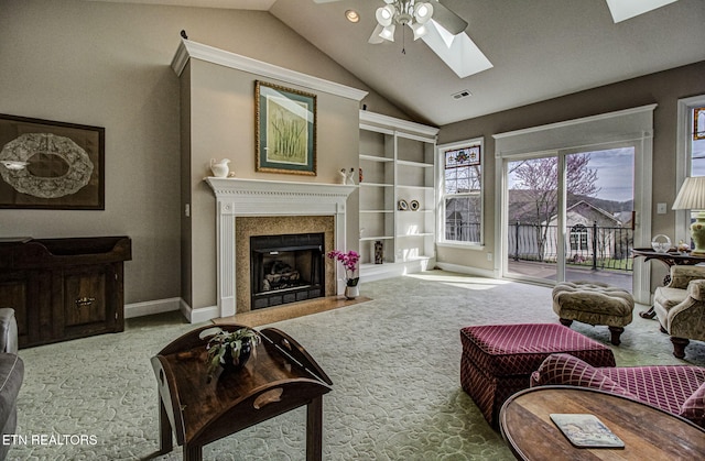 carpeted living room with ceiling fan and vaulted ceiling with skylight