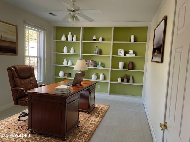 carpeted office featuring built in shelves and ceiling fan