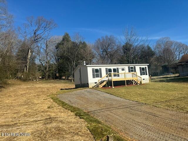 manufactured / mobile home featuring a wooden deck and a front yard