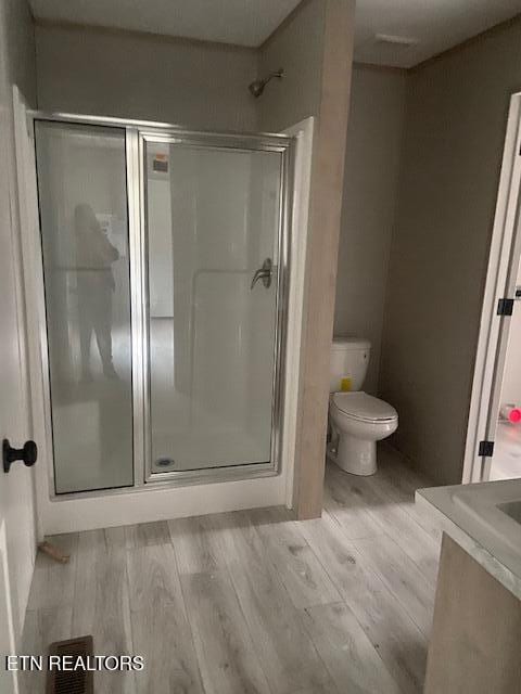 bathroom featuring an enclosed shower, hardwood / wood-style floors, and toilet