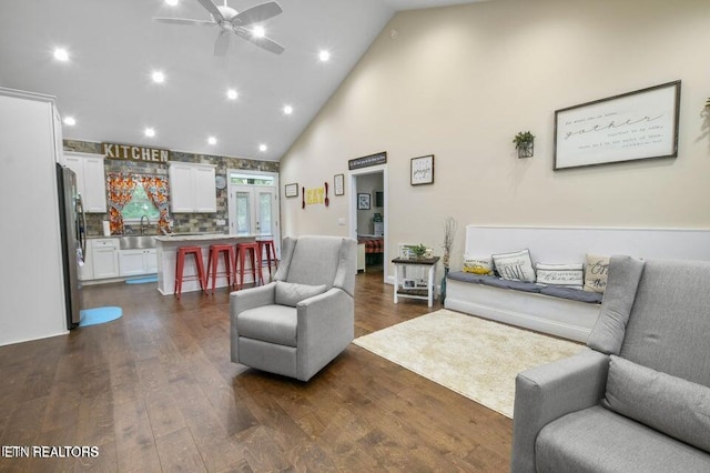 living room with dark wood-type flooring, ceiling fan, high vaulted ceiling, and sink