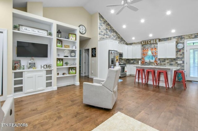 living room with ceiling fan, wood-type flooring, and high vaulted ceiling