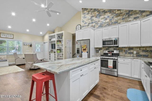 kitchen with stainless steel appliances, a center island, white cabinets, and a breakfast bar