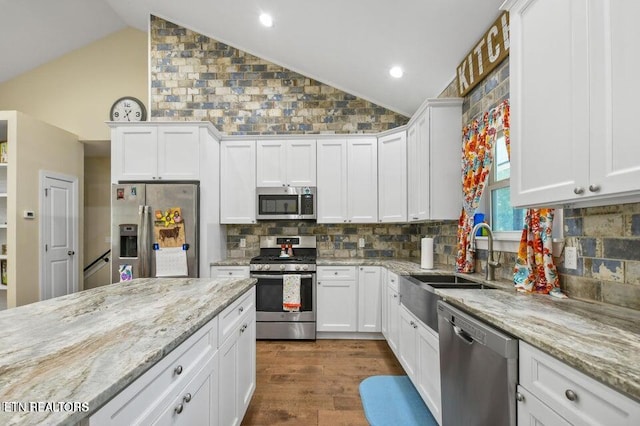 kitchen with white cabinetry, appliances with stainless steel finishes, sink, and lofted ceiling