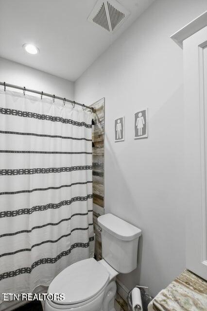 bathroom with toilet and a shower with shower curtain