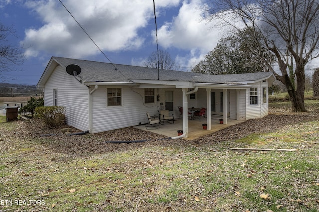 rear view of house featuring a patio and a shingled roof