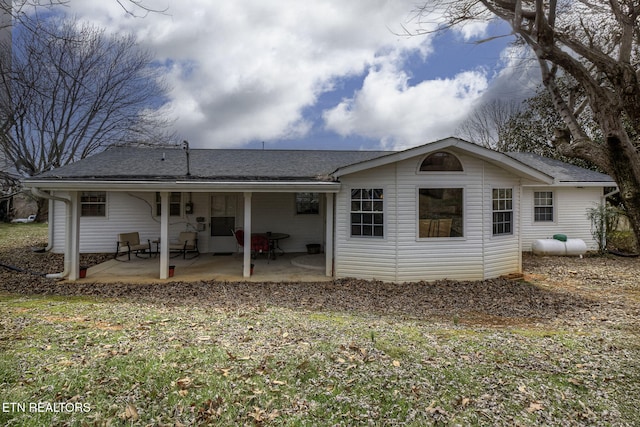 back of property with a shingled roof and a patio