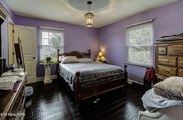 bedroom with multiple windows, dark wood-type flooring, and baseboards