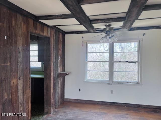 unfurnished living room featuring coffered ceiling, wood walls, ceiling fan, beam ceiling, and hardwood / wood-style floors