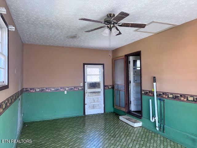 unfurnished room with ceiling fan and a textured ceiling