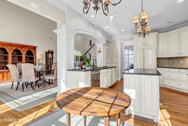 kitchen with dishwasher, an inviting chandelier, decorative columns, a center island, and decorative light fixtures