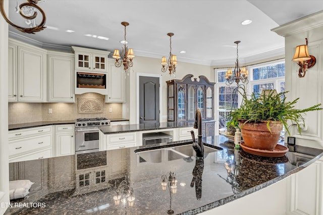 kitchen featuring decorative light fixtures, sink, dark stone counters, high end stainless steel range oven, and custom range hood