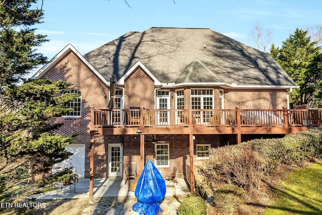 back of property with a wooden deck, a garage, and a patio area