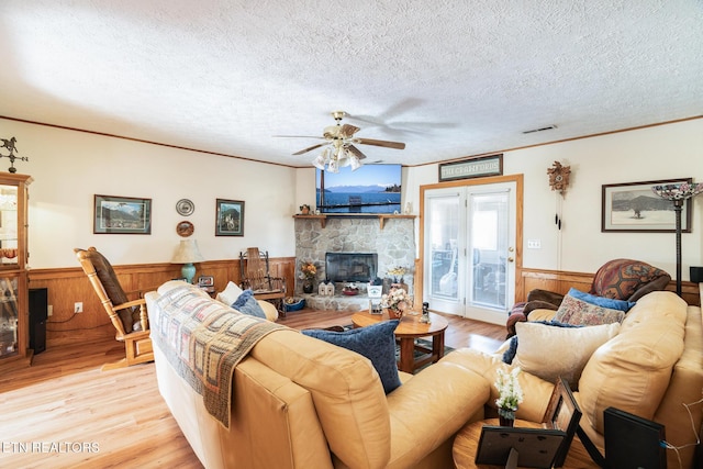 living room featuring ornamental molding, a fireplace, light hardwood / wood-style flooring, and a textured ceiling