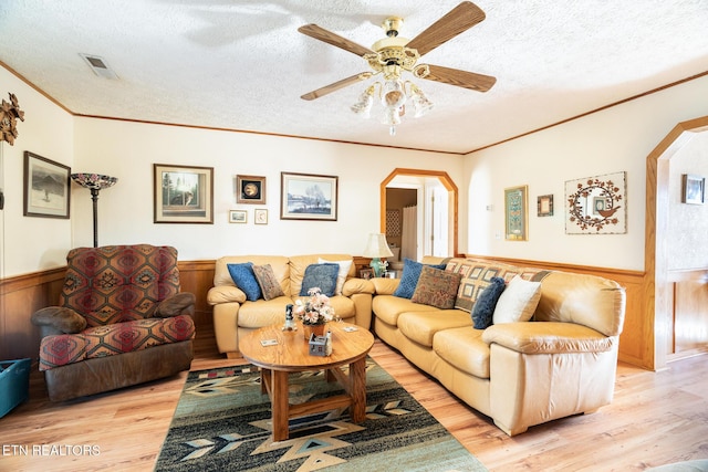 living room with ornamental molding, ceiling fan, a textured ceiling, and light hardwood / wood-style floors