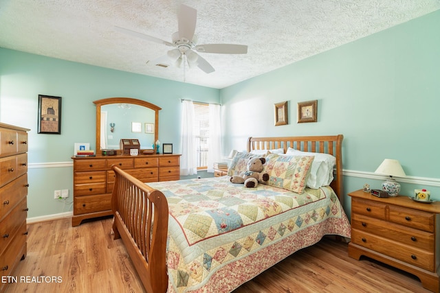 bedroom featuring ceiling fan, a textured ceiling, and light hardwood / wood-style floors