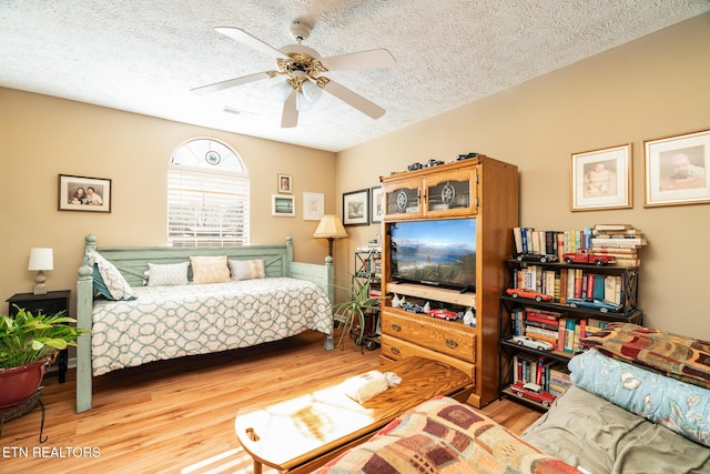 bedroom with ceiling fan, light hardwood / wood-style flooring, and a textured ceiling