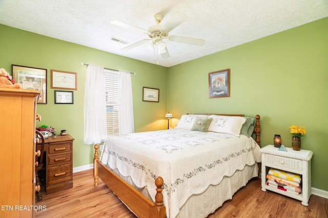 bedroom with ceiling fan, light hardwood / wood-style floors, and a textured ceiling