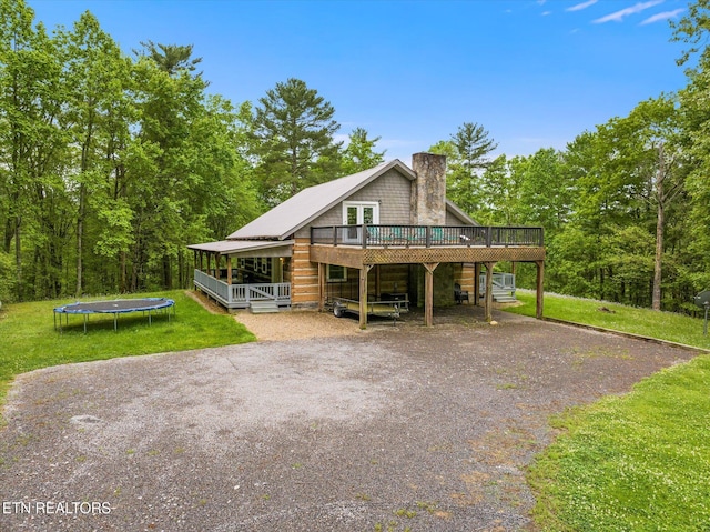 view of front of property with a wooden deck, a trampoline, and a front yard