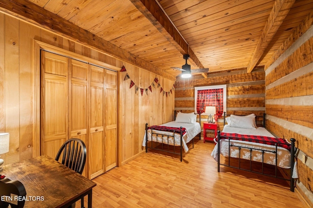 bedroom featuring light hardwood / wood-style flooring, beamed ceiling, and wood walls