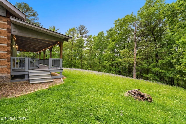 view of yard with a deck and a fire pit