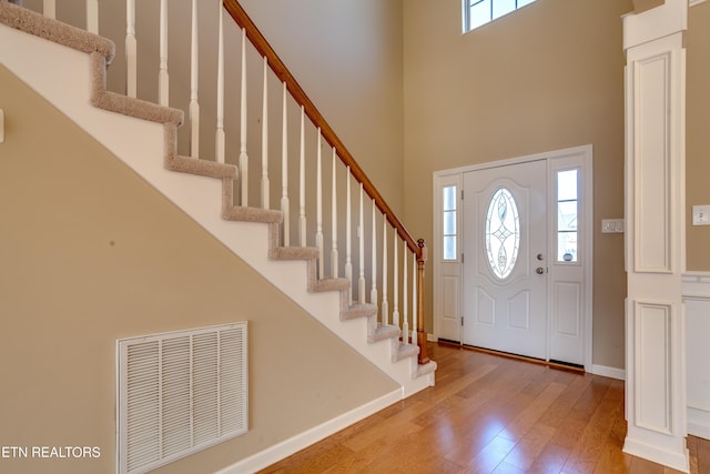 entryway with hardwood / wood-style flooring and a towering ceiling