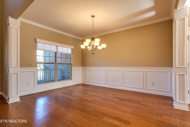 unfurnished dining area with an inviting chandelier, ornamental molding, dark wood-type flooring, and ornate columns