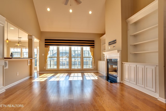 unfurnished living room with ceiling fan, high vaulted ceiling, and light wood-type flooring