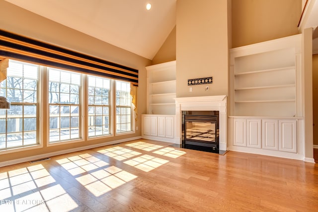 unfurnished living room featuring high vaulted ceiling, built in features, and light wood-type flooring