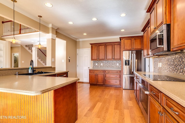 kitchen featuring pendant lighting, sink, appliances with stainless steel finishes, light hardwood / wood-style floors, and kitchen peninsula