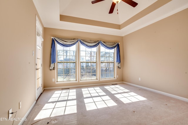 carpeted empty room featuring a tray ceiling, ornamental molding, and ceiling fan