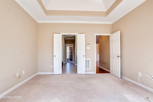 unfurnished bedroom with a tray ceiling, ornamental molding, and carpet flooring