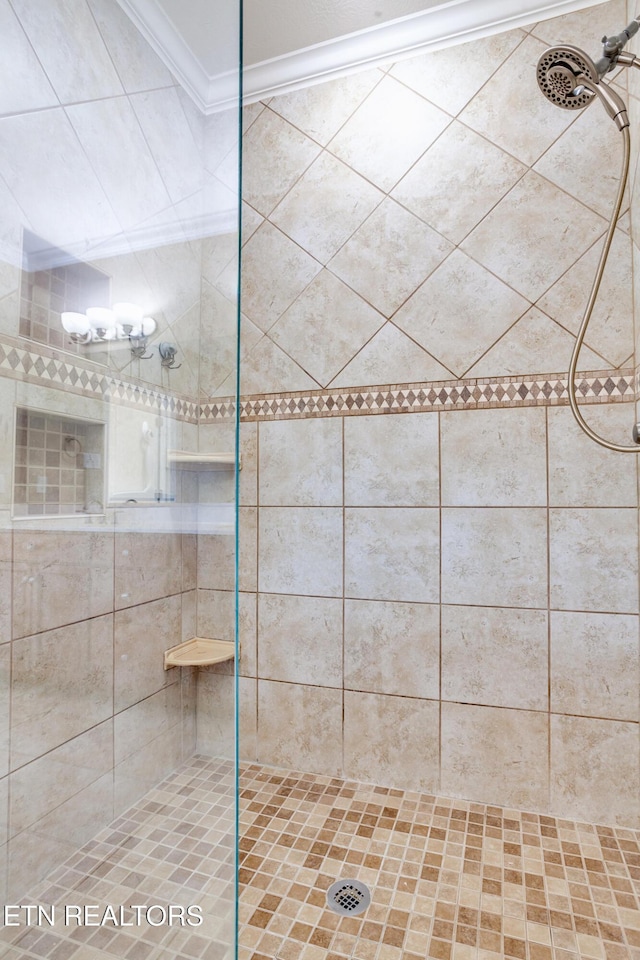 bathroom with ornamental molding and a tile shower