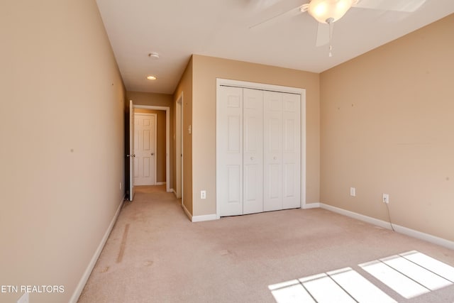 unfurnished bedroom with light carpet, ceiling fan, and a closet