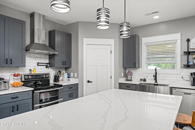 kitchen featuring sink, gray cabinetry, stainless steel appliances, light stone counters, and wall chimney exhaust hood