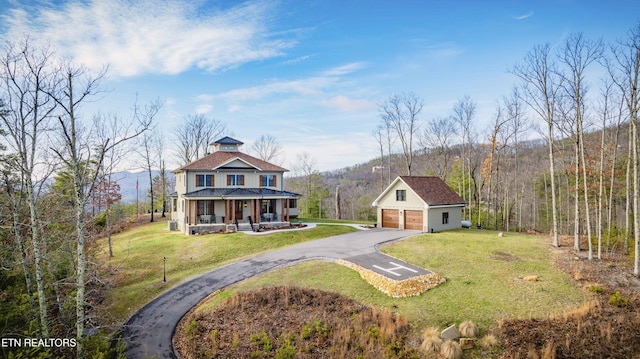 view of front facade with an outbuilding, a front yard, a garage, and a porch