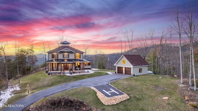 view of front facade with metal roof, covered porch, a garage, a yard, and a standing seam roof