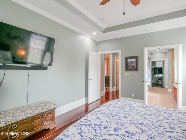 bedroom with a tray ceiling, crown molding, dark wood-type flooring, and ceiling fan