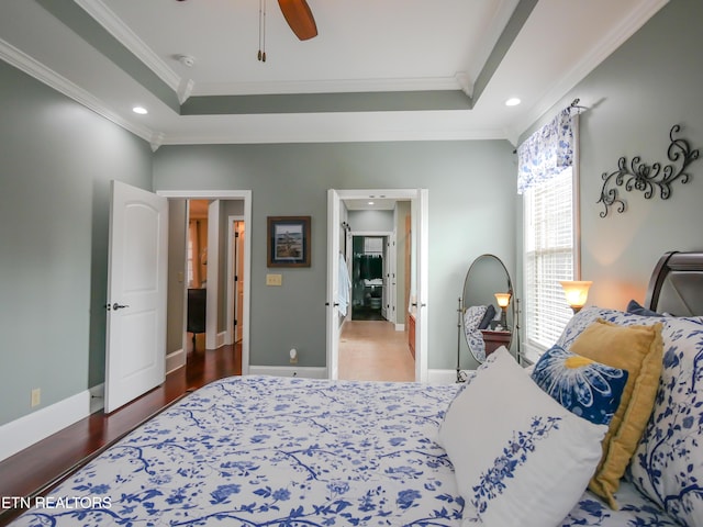 bedroom with hardwood / wood-style flooring, crown molding, and a tray ceiling