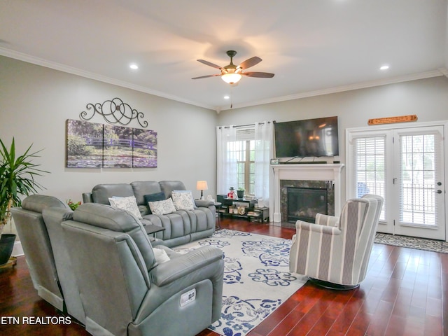 living room featuring a fireplace, crown molding, dark wood-type flooring, and ceiling fan