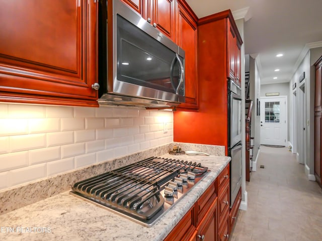 kitchen with stainless steel appliances, light stone countertops, light tile patterned floors, and backsplash