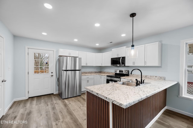 kitchen with stainless steel appliances, decorative light fixtures, light hardwood / wood-style flooring, and white cabinets