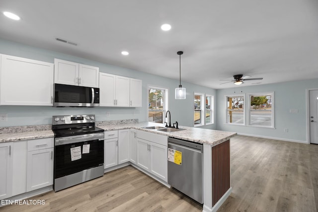 kitchen featuring sink, light hardwood / wood-style flooring, hanging light fixtures, appliances with stainless steel finishes, and white cabinets