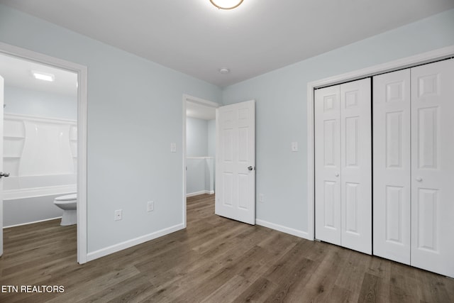 unfurnished bedroom featuring dark wood-type flooring, connected bathroom, and a closet