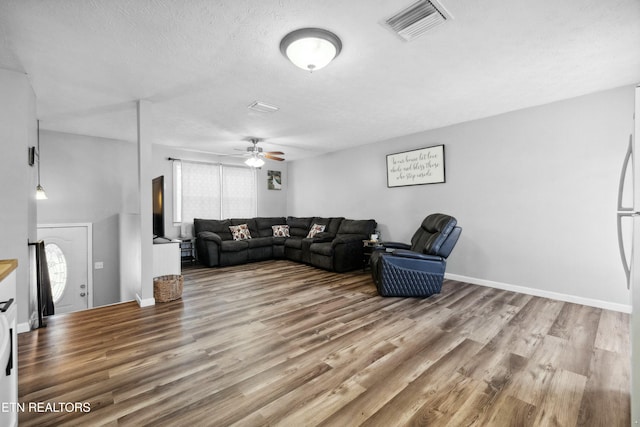 living room featuring ceiling fan, wood-type flooring, and a textured ceiling